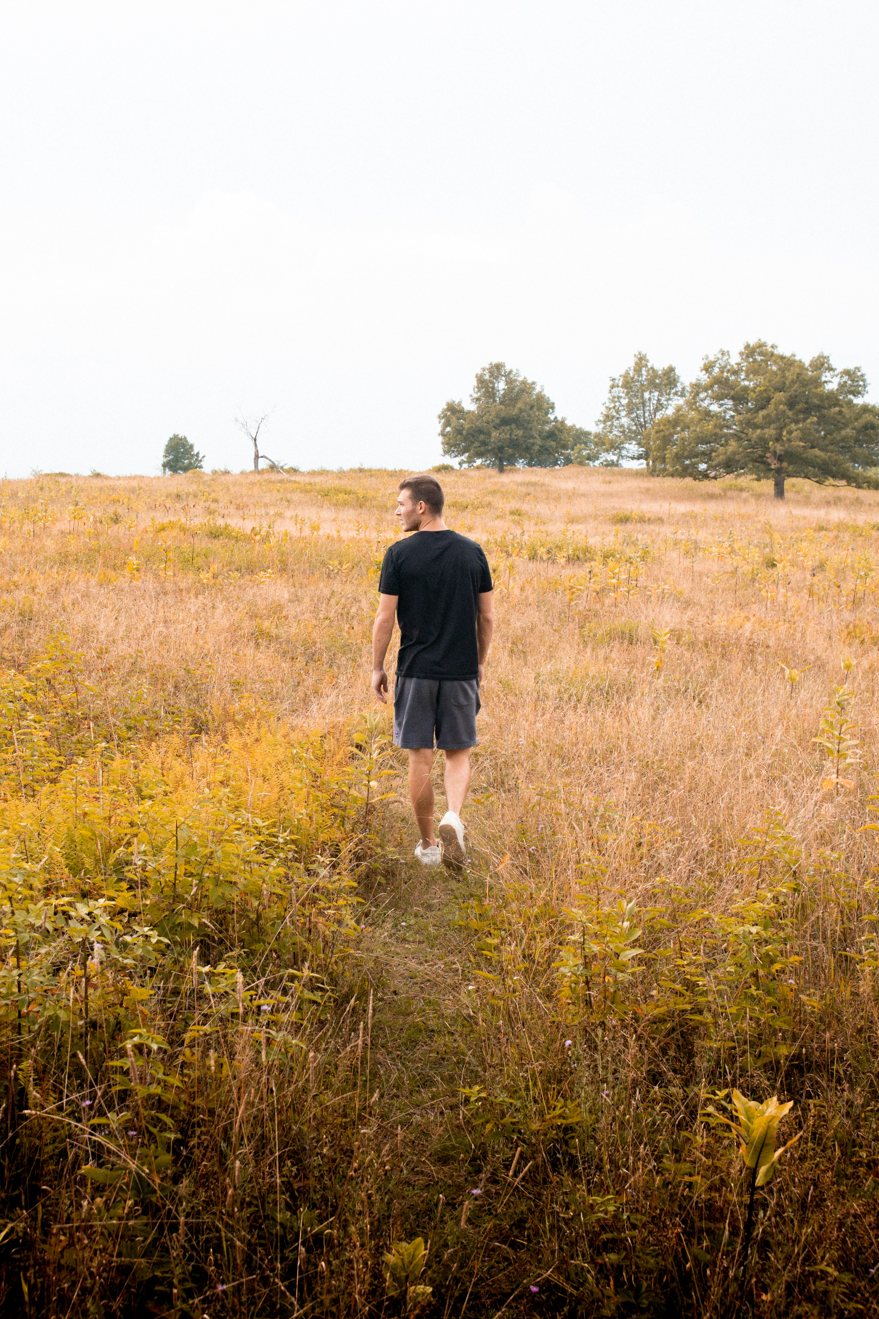 man in black shirt walking on brown grass field during daytime
